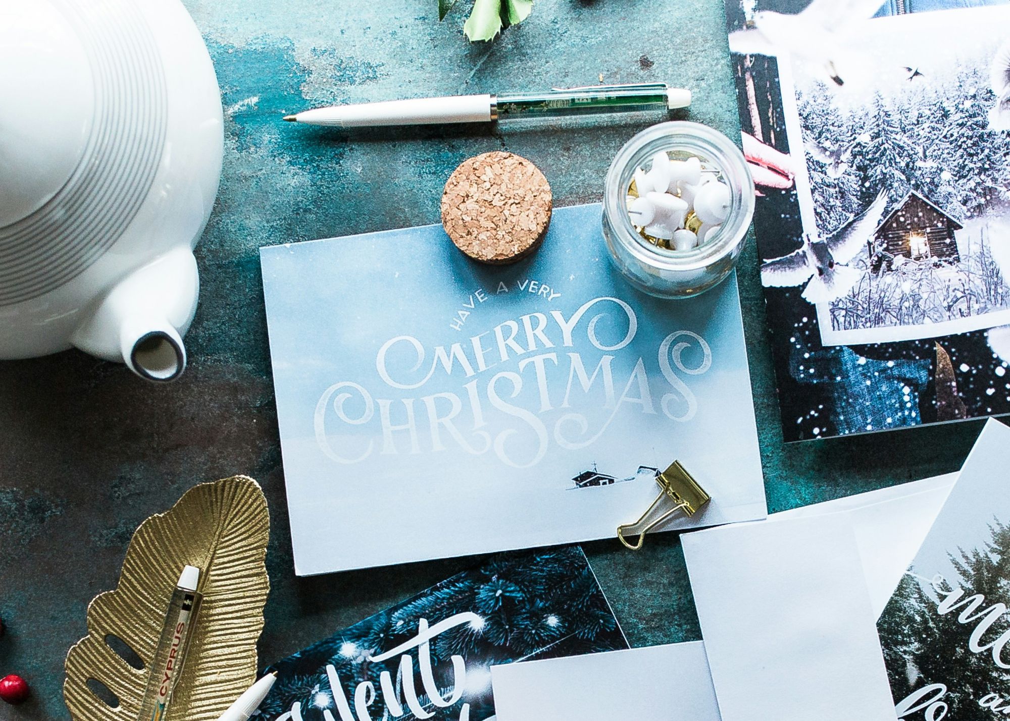 a 'Merry Christmas' Holiday card sitting on a desk with ornaments around it.